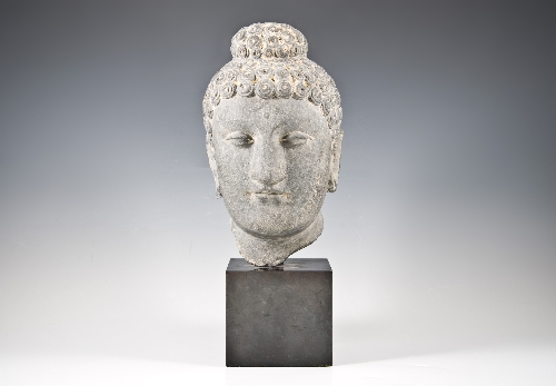 A grey schist Buddha head, probably Gandhara, almond-shaped eyes, the hair and usnisa tightly