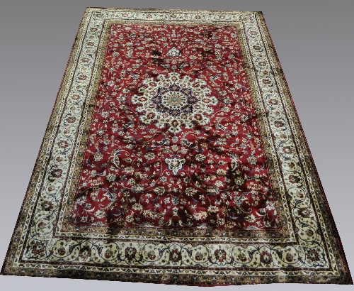 A large Kashmir machine-made rug, Tabriz style with a central medallion, on a red field, the