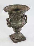 A cast iron campana shaped two handled urn, with mask handles and square plinth base, H.2ft .5in.