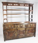 An 18th century oak dresser, with pierced and reeded frieze over three open shelves between four