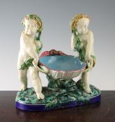 A Minton majolica centrepiece, c.1870, modelled as two vine-strewn putti pulling a scallop along a