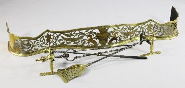 A 19th century pierced brass serpentine fender, with central armorial, winged cupids and foliate