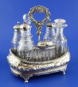 A George IV repousse silver cruet stand with six (ex seven) glass bottles, four with silver