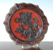 A Chinese red and black lacquer dish, early 20th century, the centre carved in high relief with