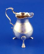 A George III silver baluster cream jug, with cut rim and scroll handle, on hoof feet, Andrew