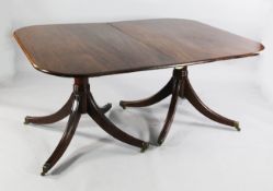 A Regency style mahogany extending dining table, the top with rounded corners and two extra