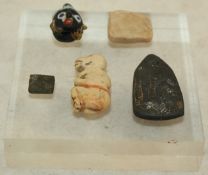 Three Egyptian stone amulets and a Syrian polychrome glass head, two amulets in marble, one of