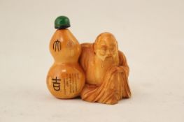A Chinese ivory figural snuff bottle, early 20th century, carved in the form of a seated immortal