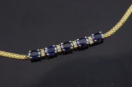 An 18ct gold, sapphire and diamond bracelet, set with 5 oval cut sapphires, bordered by