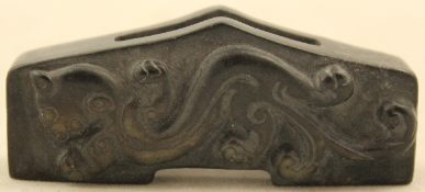 A Chinese archaistic green and black stone sword slide, carved in relief with a chi-dragon, the