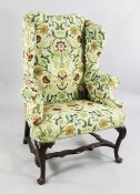An early 18th century walnut wingback armchair, with scrolling outswept arms, on cabriole legs