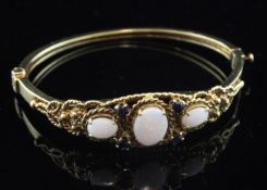 A Victorian style gold, white opal and sapphire set hinged bangle, with rope twist and bead