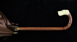 An early 20th century parasol, with walnut handle and carved ivory dog`s head finial, 33.75in.