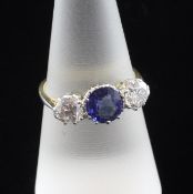 An 18ct gold three stone sapphire and diamond ring, the central round cut sapphire weighing