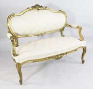 A Louis XV style carved giltwood canapé, with cartouche back and open arms, on scroll legs