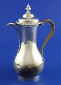 A late George II silver hot water pot, of baluster form, with engraved armorial, rattan handle and
