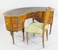 A Sheraton revival painted satinwood kidney shaped desk, decorated all over with floral bouquets,