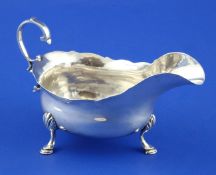 A George III silver sauceboat, with engraved initials on base, cut rim and flying scroll handle,