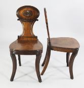 A pair of early 19th century mahogany hall chairs, the oval backs with central paterae motif, on