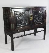 An early 20th century Chinese rosewood two door cabinet, with relief carved panels depicting figures
