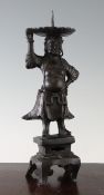 A Chinese bronze figural candlestick, late Ming dynasty, cast in the form of an immortal, standing