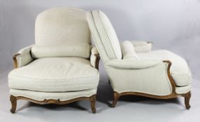A pair of French beech framed bergere chairs, beige upholstered with deep serpentine seats, on