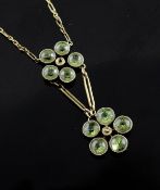 An Edwardian gold and peridot cluster set drop pendant necklace with two flower head motifs, on a