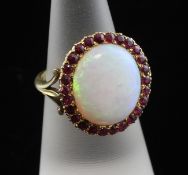 A gold, white opal and ruby cluster ring, with oval opal bordered by rubies, size L.