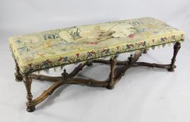 A late 17th century walnut long stool, with inverted vase turned supports united by serpentine