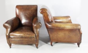 A pair of brown leather club armchairs, with scroll backs and brass studs, on turned legs and castor