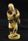 A Japanese tinted ivory figure of a farmer smoking a pipe, early 20th century, the standing figure