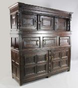 An early 17th century carved oak and chequer inlaid press cupboard, with gnarled frieze over three