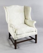 A George III mahogany wingback armchair, in cream damask upholstery, with square section legs