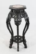 A Chinese carved rosewood octagonal urn stand, with inset rouge marble top, pierced and decorated