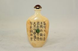 A Chinese ivory snuff bottle, early 20th century, of flattened ovoid form, one side inset with a