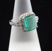 A white gold, emerald and diamond dress ring, the central stone bordered by round and baguette cut