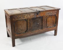 An 18th century oak coffer, with triple panel front, with scrolling leaves and stylised floral
