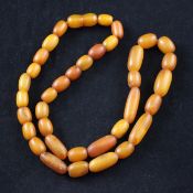 A single strand graduated oval and elongated amber bead necklace, with plastic clasp, gross weight