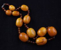 A single strand graduated oval amber bead necklace, strung with eleven oval beads and thirty one