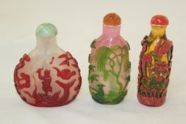 Three Chinese overlaid glass snuff bottles, 19th / 20th century, the first in red overlay carved