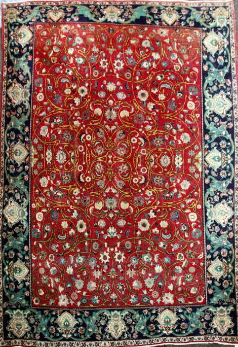 An Iranian Royal Kashan carpet, with field of scrolling foliage on a red ground, with ornate