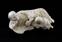 A Japanese ivory group of a man and a young boy, Meiji period, the man reclining and holding an