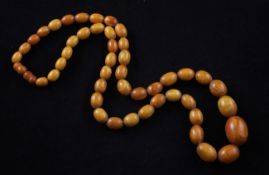 A single strand graduated oval amber bead necklace, gross 54 grams, 26in.