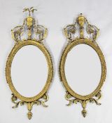 A pair of Adams style oval gilt wall mirrors, with urn and bell flower crest, with reeded frame and