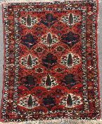 A Bakhtiari rug, with polychrome field of stylised trees amongst foliage, on a red ground, with