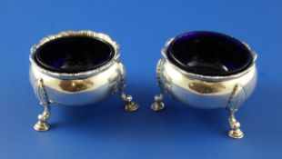 A pair of late George II silver circular bun salts, with gadrooned border and blue glass liners, on