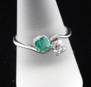 A 1920`s platinum, emerald and diamond crossover ring, set with emerald and cushion cut stones,