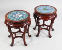 A pair of circular Chinese rosewood urn stands, the tops inset with cloisonne panels, on five