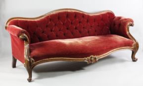 A Victorian walnut scroll end settee, with red buttoned upholstered serpentine seat, on scroll legs