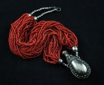 A South American multi strand coral bead necklace with base metal flask pendant mounted with